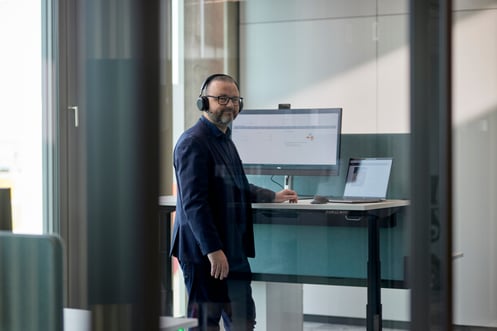 netgo Mitarbeitender im Office Berlin steht an einem höhenverstellbaren Schreibtisch