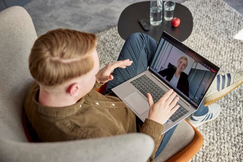 netgo Mitarbeitender sitzt auf einem Sessel und unterhält sich per Video-Call mit seiner Kollegin