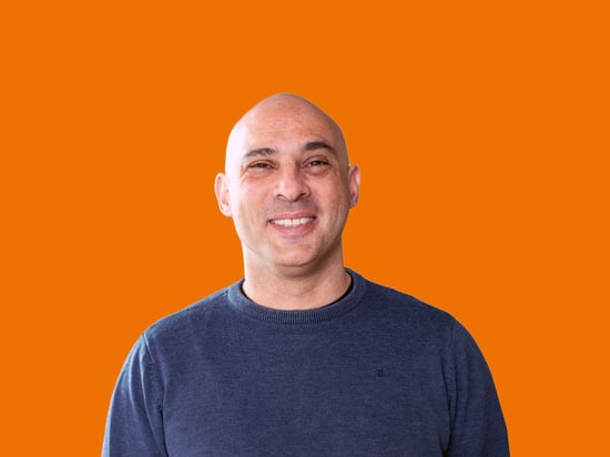 Portrait eines netgo Mitarbeitenden mit orangenem Hintergrund